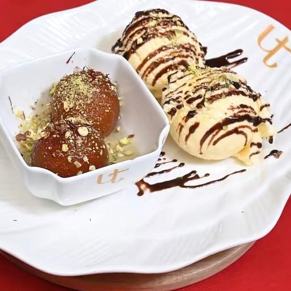 Gulab jamun with pistachios and saffron, served with vanilla ice cream drizzled with chocolate.