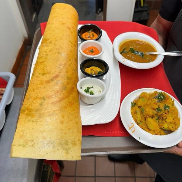 A large dosa with various chutneys, sambar, and potato curry on a tray at Urban Tandoor.